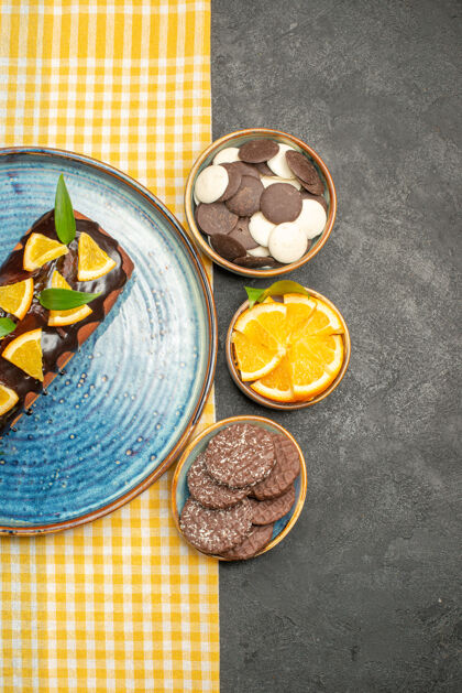 新鲜黄色条状毛巾上的美味蛋糕和黑色桌子上的饼干的垂直视图健康盘子食物