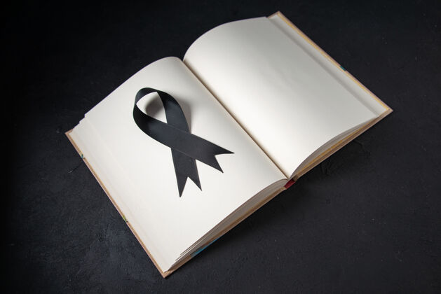 黑色蝴蝶结打开书里面黑色蝴蝶结的正面图在黑暗的表面纸张查看葬礼