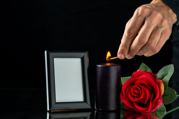 视图在黑暗的表面上有红玫瑰和画框的黑暗蜡烛的正面视图火黑暗图画