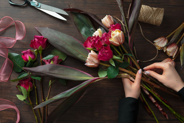 三月工作中的花店妇女在木制表面上制作时尚的现代花束女人作曲园艺