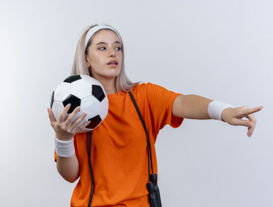 头带自信的年轻白种人运动女孩戴着牙套球背带运动