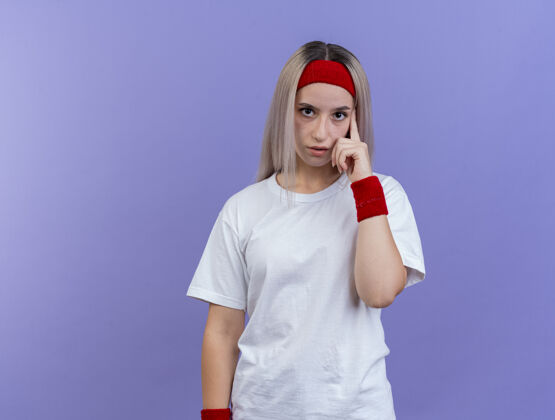 自信自信的年轻白人运动女孩戴着背带和头带运动手指头带