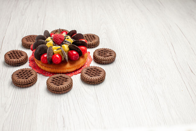 篮子左下角是红色椭圆形蕾丝小饰物上的浆果蛋糕 白色木制桌子上有饼干 有自由空间花边饼干甜点