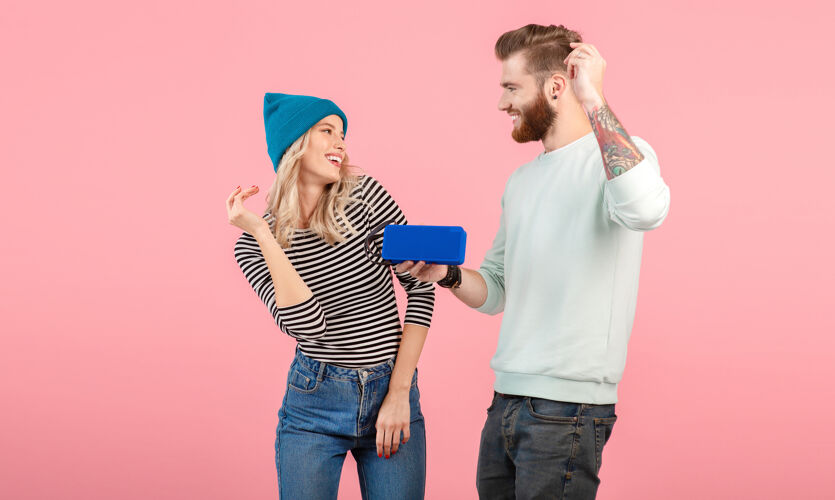 情感一对年轻夫妇穿着时尚的服装 穿着粉色的衣服 在无线扬声器上听音乐浪漫声音情侣