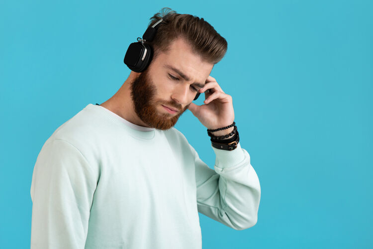 音频留胡子的男人在蓝色的无线耳机上听音乐的肖像耳机立体声脸