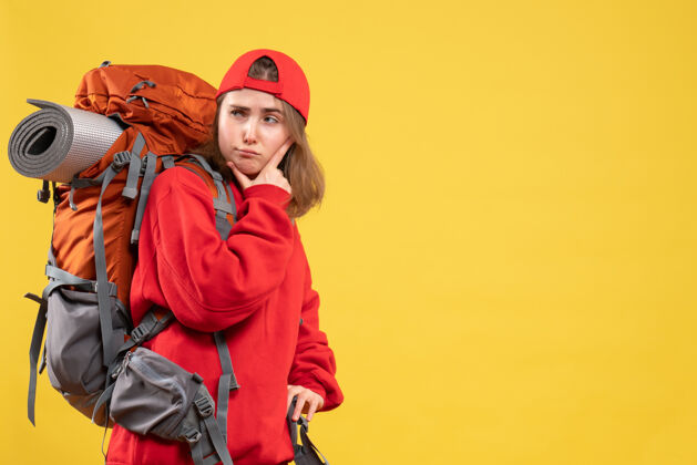 背包正面图：年轻的旅行者 手放在下巴上 背着红色背包下巴帽子成人