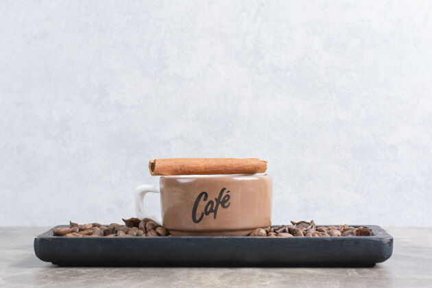 可口一杯咖啡和咖啡豆放在深色盘子里肉桂杯子咖啡