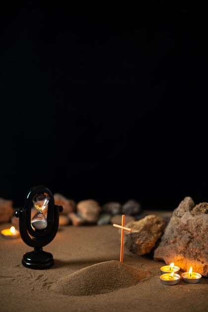 坟墓用石头点燃蜡烛 用沙子上的小坟墓来纪念葬礼上的死亡黑计时器肖像