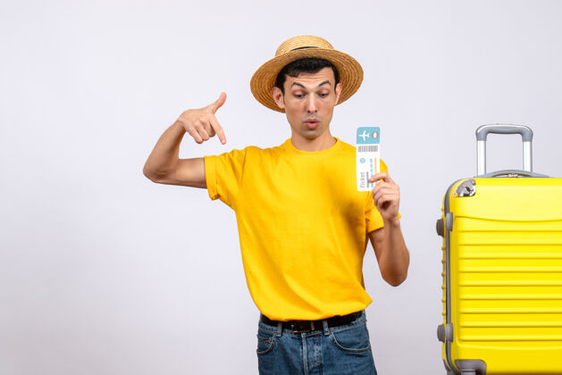 男正面图穿着黄色t恤的年轻人站在黄色手提箱旁 指着下面年轻人黄前面