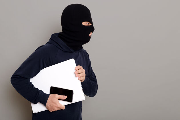 盗窃一个罪犯带着偷来的笔记本电脑逃跑的侧视图恶棍窃贼监狱
