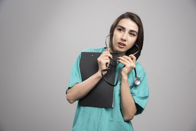 工作女医生在灰色背景上使用听诊器高质量照片健康年轻人医生