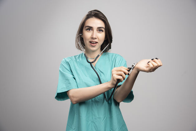 工作女医生用听诊器检查自己的灰色背景高质量的照片个人年轻人医疗
