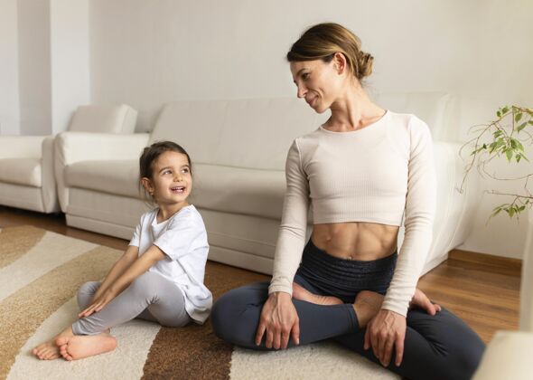 锻炼坐在地板上的妈妈和女孩运动活跃训练