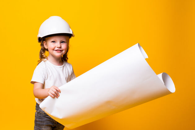 肖像戴着建筑头盔的小女孩建筑师 黄色的墙上贴着隔离的海报建筑工程师可爱