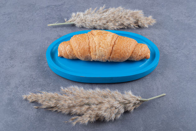 新鲜自制新鲜羊角面包放在蓝色木板上自制营养许多
