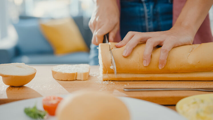 切片年轻的亚洲女厨师手拿刀在木板上切全麦面包有机烹饪厚