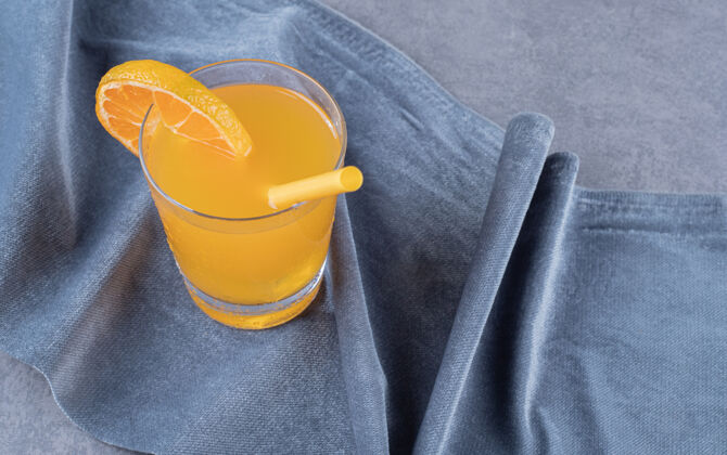 玻璃杯在灰色背景上拍摄新鲜橙汁的特写照片新鲜水果健康