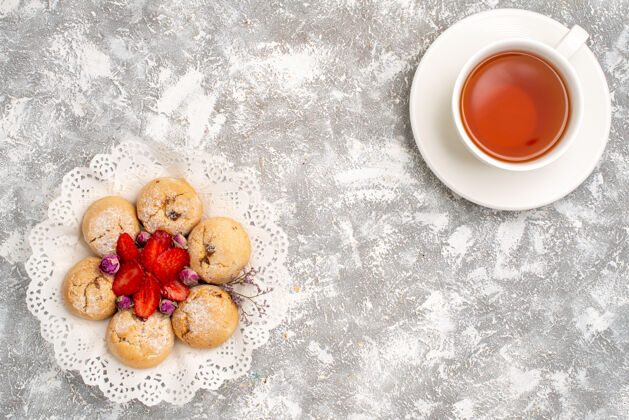 饼干俯瞰美味的沙饼干与新鲜草莓和一杯茶在白色的表面饼干杯子马克杯