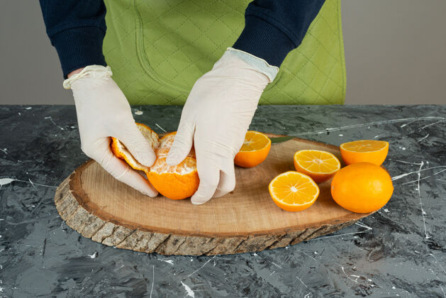 围裙男手戴手套在桌上剥鲜橘子各种水果切片