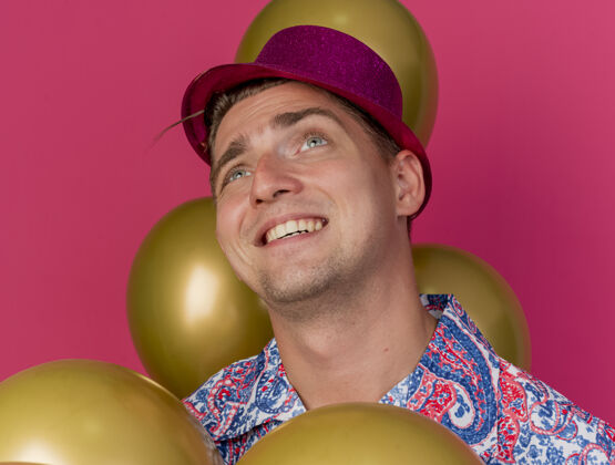 等等微笑的年轻人戴着粉红色的帽子站在粉红色的气球孤立党年轻人派对气球