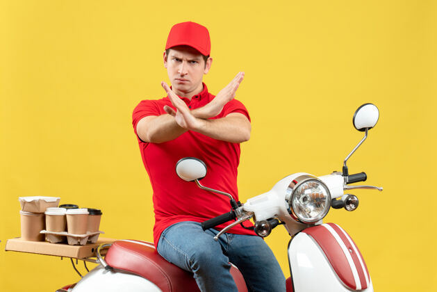 背景前视图紧张的年轻人穿着红色上衣 戴着帽子 在黄色背景下发出停止的手势年轻人红色车辆