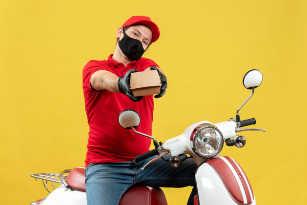 车辆俯视图：身穿红色上衣 戴着帽子手套 戴着医用面罩的快递员坐在滑板车上下命令头盔红色摩托车