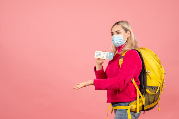 模型正面是一个戴着面具的旅行妇女 在粉红色的墙上拿着票票时尚女旅客