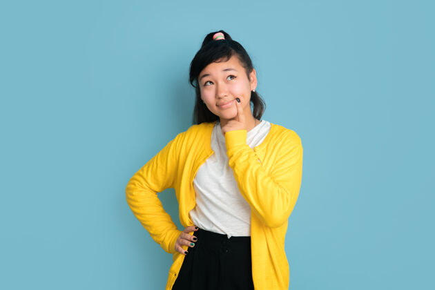 衬衫在蓝色工作室背景上孤立的亚洲青少年肖像美丽的深褐色女性模特 随意的长发人类情感的概念 面部表情 销售 广告梦幻青少年亚洲人成功