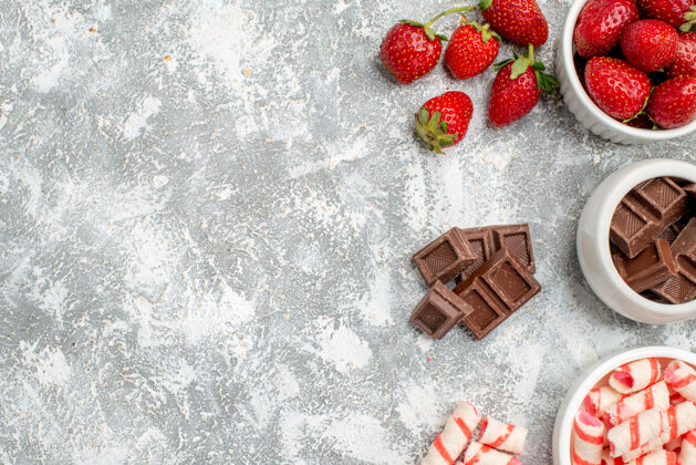 甜点在灰白色地面的右侧 有草莓巧克力糖果和一些草莓巧克力糖果的顶视图碗权利食物草莓