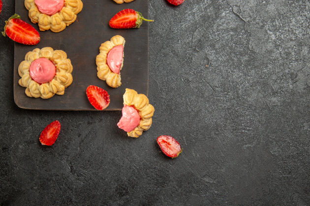 奶油灰色表面上有草莓奶油的小甜饼俯视图饼干图钉糖