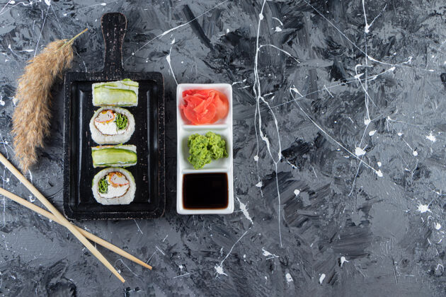 餐黑色木板 大理石背景上有青龙寿司卷黄瓜新鲜鱼