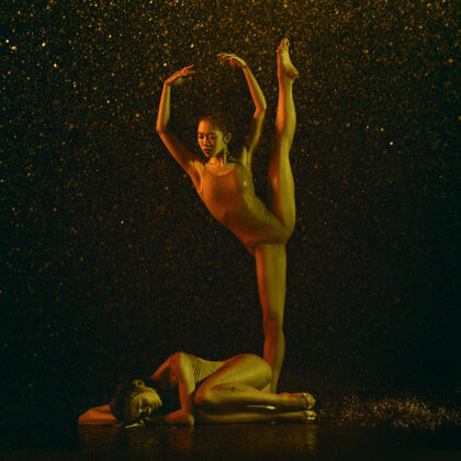 下降睡觉两个年轻的女芭蕾舞演员在水滴和浪花下白种人和亚洲模特在霓虹灯下一起跳舞芭蕾舞和当代舞蹈概念创意艺术照片身体喷雾编舞