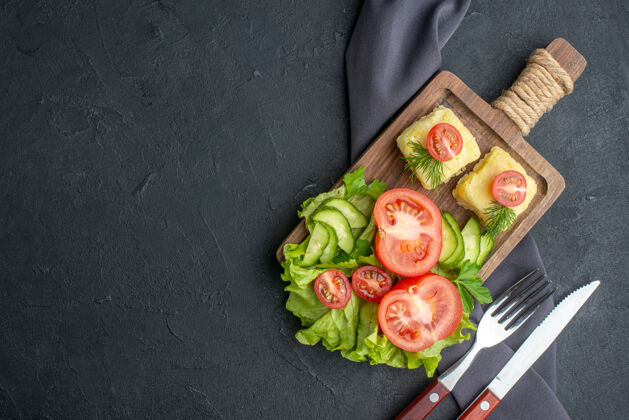 生的侧视图切新鲜番茄和黄瓜奶酪在木板上左侧的黑色表面午餐美食饮食
