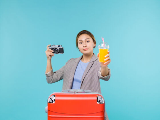 航行前景度假中的女性手持新鲜果汁和相机在淡蓝色的背景下海上度假旅行光旅行相机