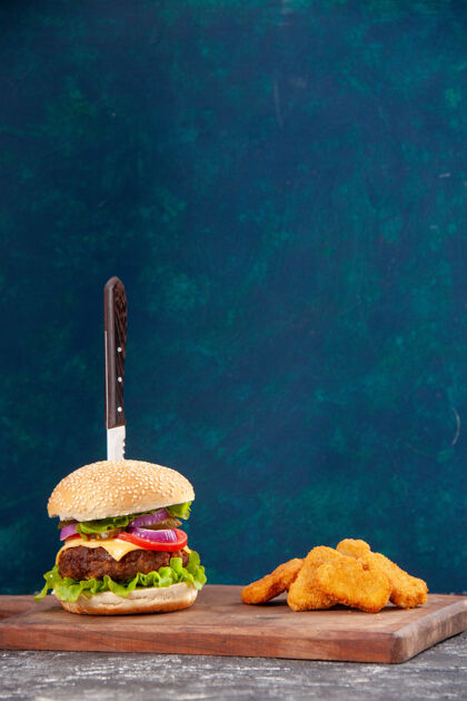 水刀在美味的肉三明治和鸡块在深蓝色的木板上的垂直视图海肉三明治水生
