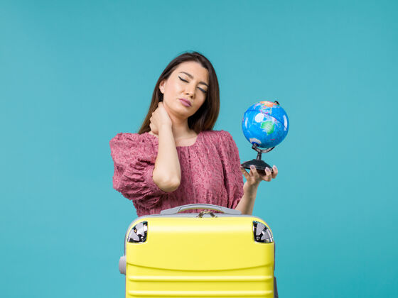 前面前景度假女抱着蓝色背景上的小地球仪旅行海女旅行暑假女人地球旅行