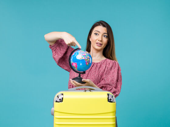 前面前景度假女抱着小地球仪在蓝色的背景上出海度假女旅行避暑小假期旅行
