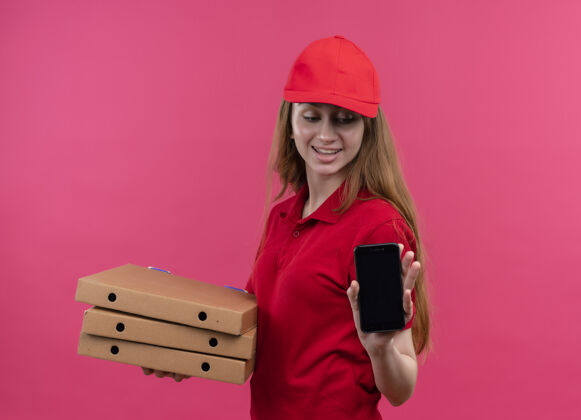 送货微笑的年轻送货女孩拿着包裹和手机 看着手机上孤立的粉红色空间抱着微笑粉色