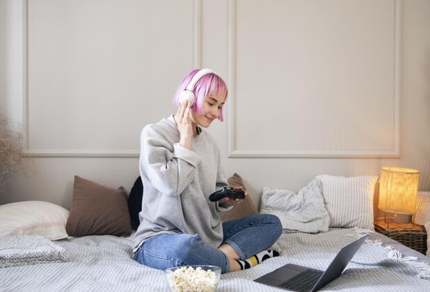 娱乐粉红色头发的年轻女子在玩电子游戏享受技术虚拟