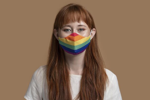 爱戴着彩虹医学面具的年轻红发女人自豪女同性恋运动