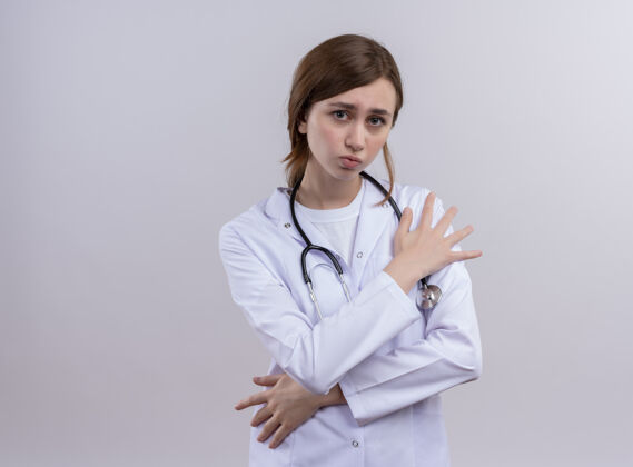 年轻悲伤的年轻女医生穿着医用长袍和听诊器把双手放在肩膀和腰部与复制空间手穿女性