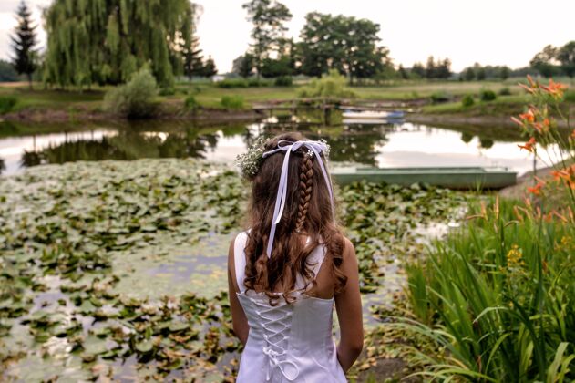 仪式美丽的女人站在美丽花园的池塘前花女士年轻