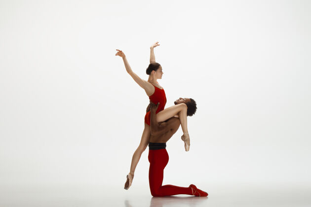 人优雅的经典芭蕾舞者在白色的工作室背景上独立地跳舞一对穿着鲜红衣服的舞者就像是酒和牛奶的结合优雅 艺术家 动作 动作的概念优雅芭蕾舞织物