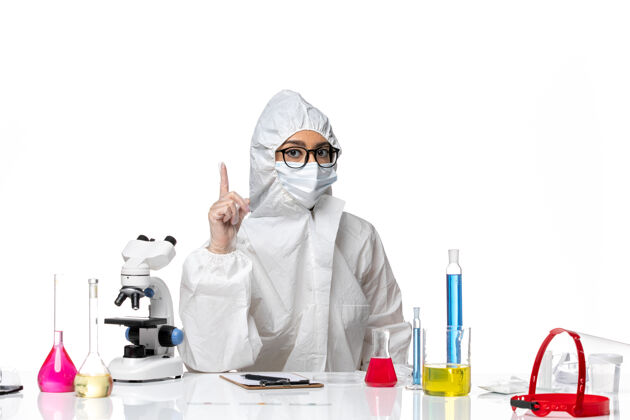 正面前视图穿着特殊防护服的女化学家坐在白色化学背景上解决病毒大流行流行病白人坐姿