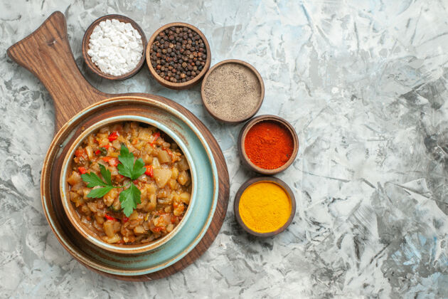 胡椒顶视图烤茄子沙拉碗和不同的香料碗在灰色的表面烹饪健康一餐