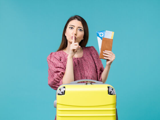 票正面图度假中的女性拿着她的钱包和浅蓝色背景的机票旅行女性暑假风景旅行安静
