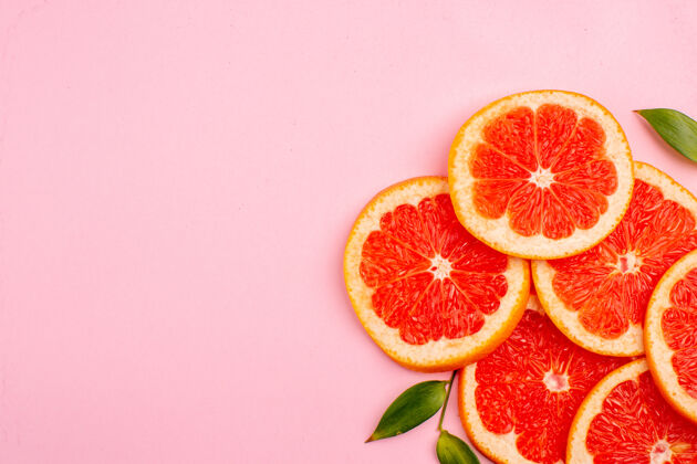 果汁粉红色表面上美味的葡萄柚和多汁的水果片的俯视图可食用水果新鲜农产品