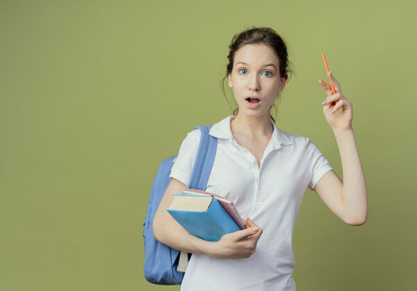 背令人印象深刻的年轻漂亮的女学生戴着背袋拿着记事本和提书笔孤立在橄榄绿的背景与复印空间拿着年轻包