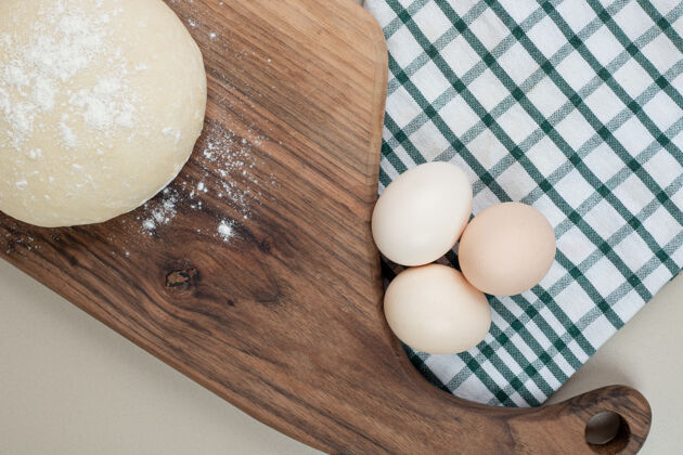堆木砧板上放三个新鲜鸡蛋的面团烘焙木头面粉