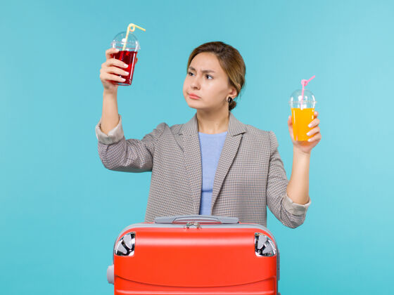 工作前视图：度假中的女性手持新鲜饮料乘坐蓝色背景的旅行度假海上飞机前方蓝色举行